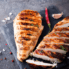 Poitrine de poulet grillée sur une planche en bois, accompagnée d'un piment frais et d'une gousse d'ail - saveurs intenses Pour Le Chef