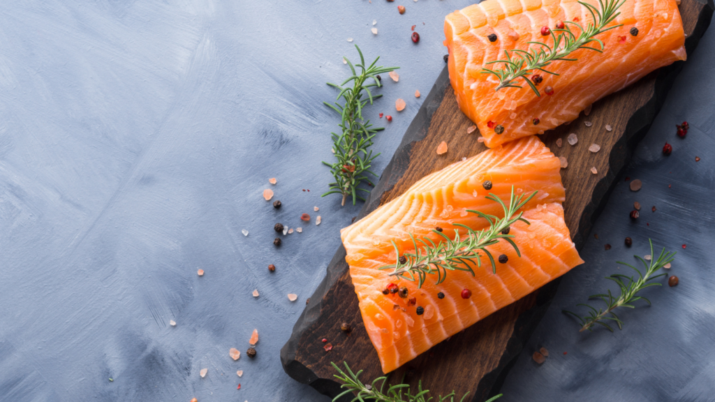 Deux pavés de saumon biologique disposés sur une planche en bois garnie de fines herbes fraîches - qualité supérieure Pour Le Chef