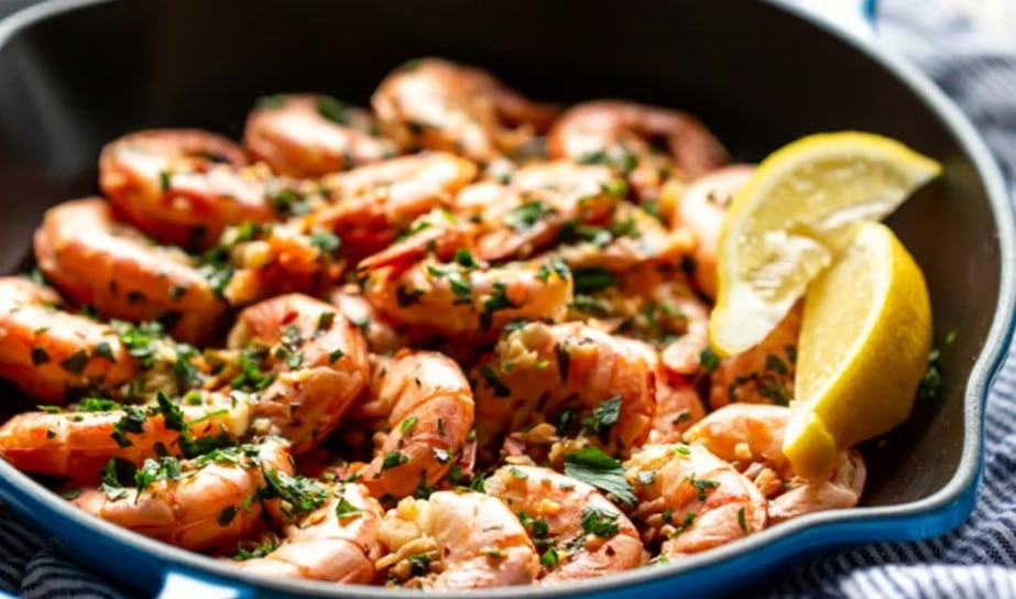 Poêle avec crevettes d'Argentine cuites dans du beurre d'ail, persil frais et citron, prêt à être servi.