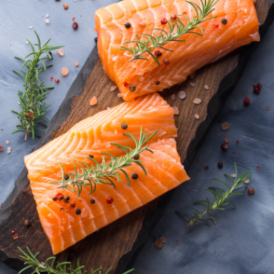 Deux pavés de saumon biologique disposés sur une planche en bois garnie de fines herbes fraîches - qualité supérieure Pour Le Chef