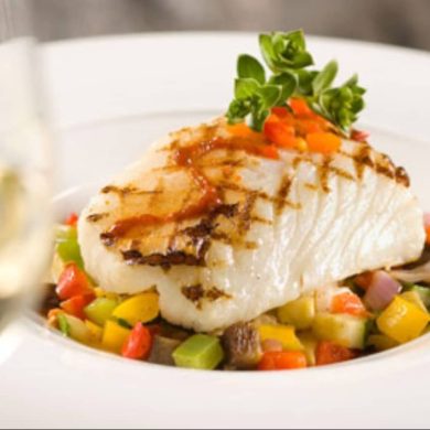 Pavé de bar du Chili sur un lit de légumes, accompagné d'un verre de vin blanc — assiette colorée et savoureuse Pour Le Chef